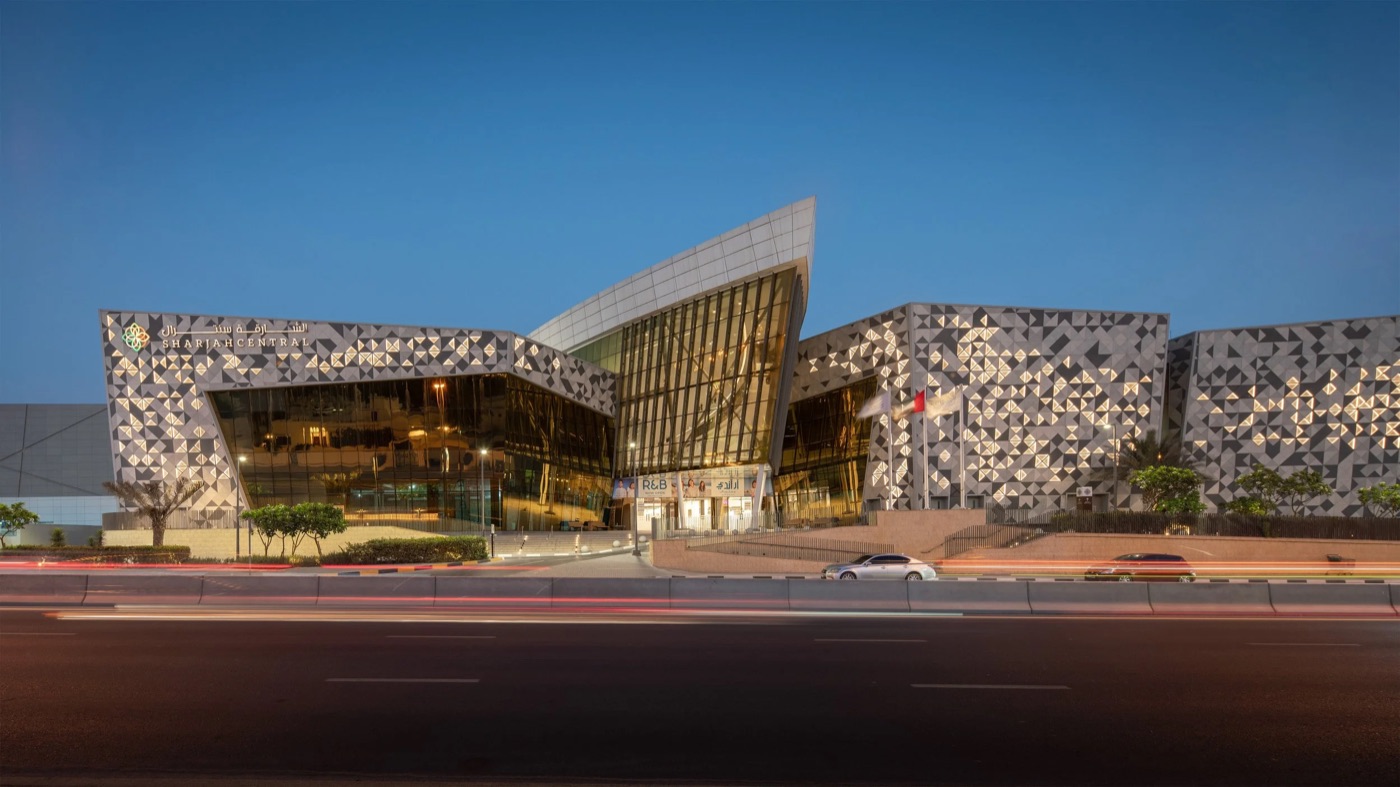 Sharjah Central mall at dusk, lit up with its geometric facade